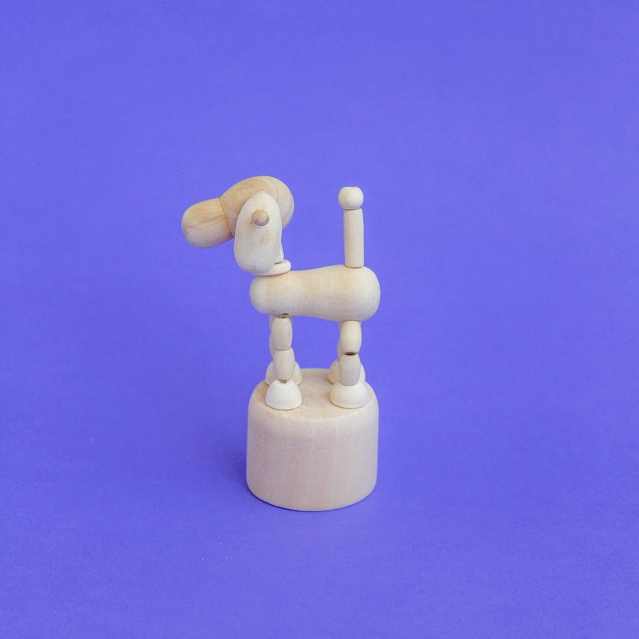 Perrito de madera articulado visto de perfil sobre fondo morado