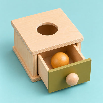 Caja de permanencia con el cajón verde oliva abierto y la pelota ocre dentro