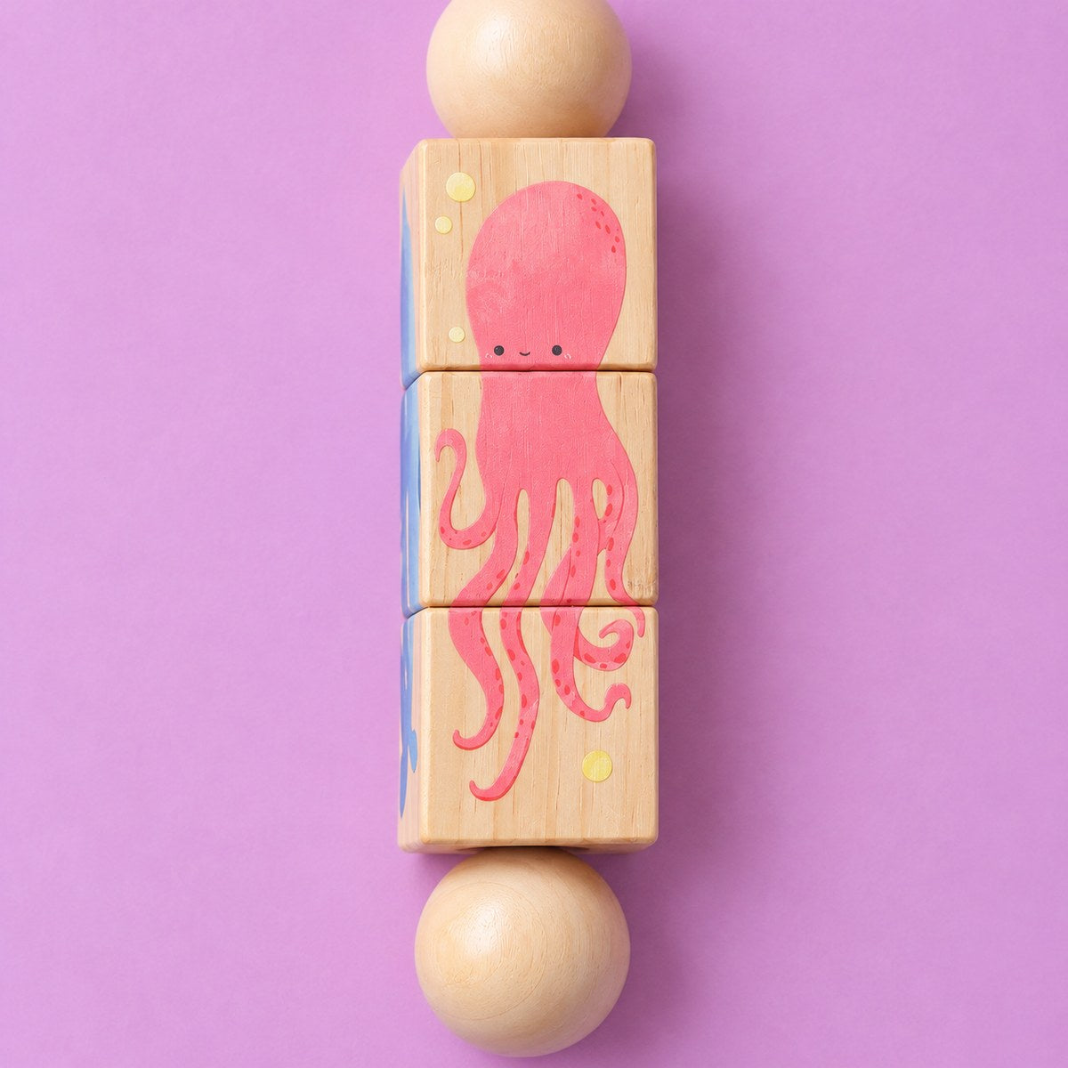 Detalle del lado del pulpo rosa con carita, pintado sobre los tres cubos de madera del sonajero