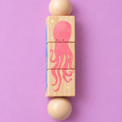Detalle del lado del pulpo rosa con carita, pintado sobre los tres cubos de madera del sonajero