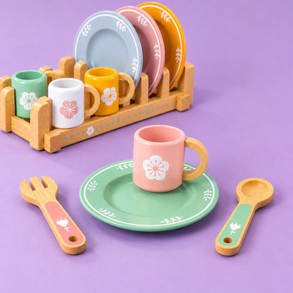 La taza rosa con su asa de anillo sobre el plato verde, con el escurridor detrás